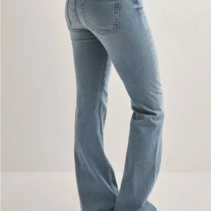 Ljusblå bootcut jeans med rå kant - Snygga ljusblå jeans med bootcut passform och rå, fransad midjekant. Jeansen har klassisk femficksdesign och är tillverkade i mjukt denimtyg som ger en skön känsla. Perfekta för dig som gillar en avslappnad men trendig look.