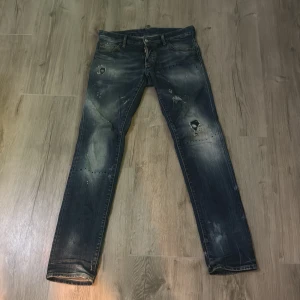 Dsquared2 blå jeans  - Snygga blå jeans från Dsquared2 i slim fit-modell med slitna detaljer och hål på benen. Jeansen har klassisk femficksdesign, tydliga slitningar och en cool tvätt. Dsquared2-logga vid gylfen. Perfekta för dig som gillar streetstyle.