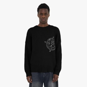 Svart stickad tröja från Vicinity - Svart stickad tröja från Vicinity med stort broderat logomärke på bröstet. Tröjan har en grovstickad struktur, rund halsringning och långa ärmar. Perfekt för dig som gillar streetwear och vill ha en snygg statement piece i garderoben.