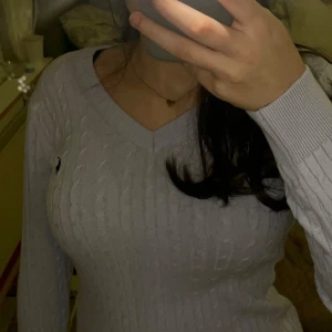 Ljuslila stickad polo tröja - Säljer en ljuslila stickad polo tröja med v-ringning och långärmad design. Tröjan har ett diskret märke på bröstet och ribbade detaljer vid ärmslut och nederkant. Perfekt för kyligare dagar! Ej använd och säljer då jag drog av etiketten så kan ej returnera.