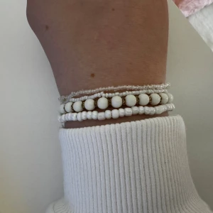 Set med vita pärlarmband - Säljer ett set med fyra pärlarmband i olika stilar. Två armband har små vita pärlor, ett har större vita pärlor med guldfärgade detaljer mellan varje pärla och ett har genomskinliga pärlor. Perfekt att mixa och matcha för en fräsch och clean look.                Vet ej vart de är ifrån, aldrig använda.                    Skickar ditt köp inom 24h!💘