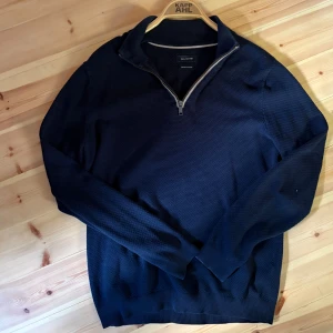 Marinblå half zip tröja Paul Hunter - Snygg marinblå tröja från Paul Hunter med half zip och krage. Materialet har en diskret struktur som ger en cool känsla. Perfekt för dig som gillar stilrena och bekväma plagg. Långärmad modell med ribbad krage och muddar.