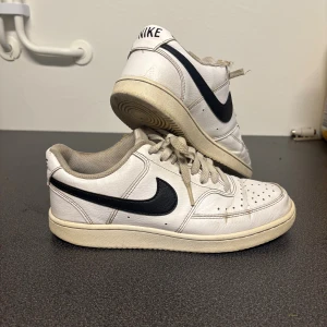 Vit/svarta nike skor - Använda en del, men med omsorg. Defekterna är nötta på insidan (bild 3), nedtrampade/nötta i hälen (bild 4) och creasade (bild 5)