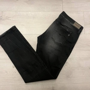 Replay Anbass svarta jeans, 31/32 - Svarta Replay Anbass jeans med snygg tvättad look och klassisk femficksdesign. Modellen har en slim passform och raka ben, med diskreta detaljer och logopatch bak. Materialet är mjukt jeans-tyg som sitter skönt hela dagen.