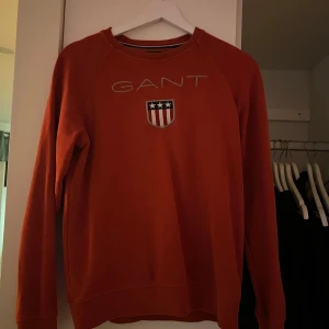 Gant Sweatshirt - Säljer en röd gant sweatshirt. Köpt från kidsbrandstore. Är i jättefint skick förutom en liten blekt fläck på ryggen. Är barnstorlek men är stor i storleken. 