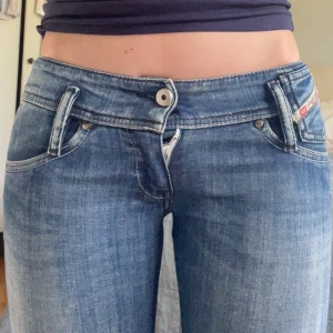 Diesel blå lågmidjade jeans - Säljer ett par klassiska blå jeans från Diesel med låg midja och raka ben. Jeansen har fem fickor och tydliga sömmar. Perfekta för dig som gillar Lågmidjade jeans, man kan även klippa dom till shorts om man inte gillar dom raka benen💕💕säljer då dom är för små💕
