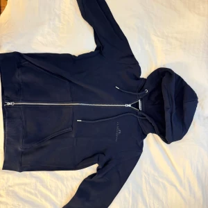 Marinblå hoodie från J.Lindeberg - Snygg marinblå hoodie från J.Lindeberg med dragkedja och huva. Aldrig använd, skickas samma dag och mer bilder kan ordnas Mvh!