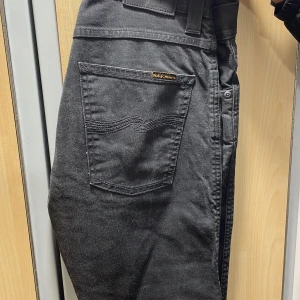 Svarta jeans från Nudie Jeans Co 32/32 - Svarta jeans från Nudie Jeans Co i klassisk femficksmodell. Jeansen har raka ben, snygga svarta sömmar och diskret logga på bakfickan. Tillverkade i mjukt bomullstyg med en stilren look som passar perfekt till sneakers eller boots.