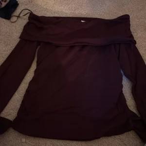 Vinröd offshoulder topp Gina Tricot - Snygg vinröd offshoulder topp från Gina Tricot med långa ärmar och bred kant upptill. Tunn och mjuk, perfekt för dig som gillar stilrena plagg med en twist. Passformen är normal och tyget känns lätt mot huden.