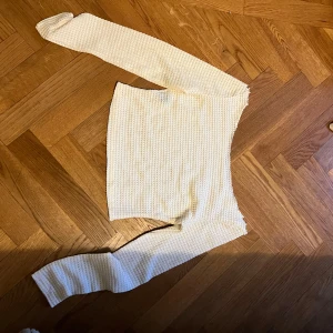 Vit stickad tröja med struktur - Säljer en vit stickad tröja med lång ärm och snyggt strukturerat mönster. Tröjan har en rak passform och är perfekt för lager-på-lager. Enkel och stilren design som passar till det mesta.