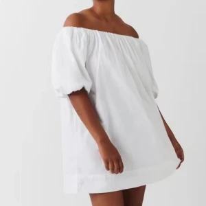Vit offshoulder kortklänning - Superfin vit kortklänning med offshoulder och puffiga korta ärmar. Klänningen har en luftig och loose passform, perfekt för varma dagar. Tillverkad i ett lätt bomullstyg som känns fräscht och bekvämt. Perfekt till student!