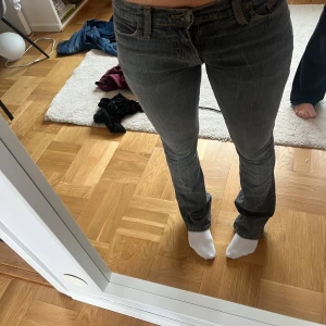 Grå jeans från Puss&Kram med broderi - Snygga grå jeans från Puss&Kram med coolt broderi av en örn i gult och vitt på bakfickan. Jeansen har klassisk femficksmodell och normal passform. Det ända är att på bakfickan är det en lagning (se bild 4) men skulle inte säga att man lägger märke till de alls, de smälter in väldigt bra! Hör av er vid frågor mm💗