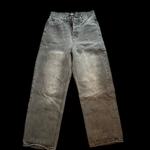 Svarta Jeans Från Balenci - Säljer ett par svarta Balenci jeans i modellen Unifit. Jeansen har en loose och wide passform med raka ben och klassisk femficksdesign. Materialet är robust denim i bomull och färgen är tvättad svart med slitna detaljer för en cool vintagekänsla.