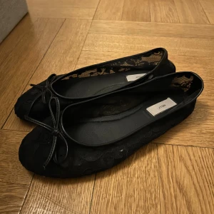 Svarta spetsballerinaskor från Nelly - Säljer snygga svarta ballerinaskor från Nelly. Skorna är täckta med blommig spets och har en platt sula för skön komfort. Riktigt bekväma!💞