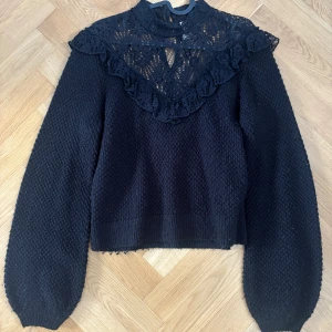 Svart stickad tröja med spets och volang - Svart stickad tröja med långa ärmar som är lite vidare. Från h&m, divided. Den är lite nopprig vilket syns på bilderna men inget man tänker mycket på i verkligheten!