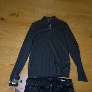 Mörkgrå half zip tröja Jack & Jones - Mörkgrå långärmad tröja från Jack & Jones med half zip-dragkedja i halsen. Tröjan har en stilren och enkel design med ribbade muddar och är tillverkad i mjukt material som känns skönt mot huden. Perfekt för lager-på-lager under kyliga dagar.