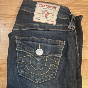 True Religion Becca Bootcut Jeans - Mörkblå jeans från True Religion, modell Becca Mid Rise Bootcut. Jättefina❤️ Ända dåliga är en liten svart fläck på låret. Köptes för 1200 kr och säljer för 700 kr