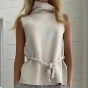 INTRESSEKOLL💕💕 - Beige stickad väst från Zara med hög polokrage och knytband i midjan. Västen är ärmlös och har en mjuk, lätt oversized passform som ger en chill vibe. Perfekt att styla över en skjorta eller långärmad tröja för en trendig lager-på-lager-look.