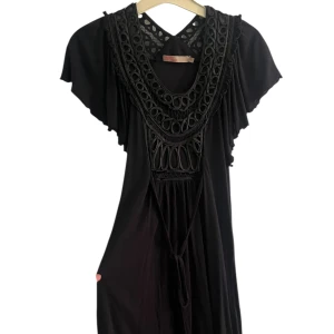 Svart långklänning med spetsdetaljer - Svart långklänning med snygga spetsdetaljer och dekorativa utskärningar vid halsen. Klänningen har vida, korta ärmar och är ganska flowy. Har knytband i midjan.