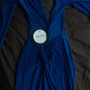 NA-KD Klänning - Blå långklänning från NA-KD med djup v-ringning samt låg rygg och långärmade ärmar. Materialet är mjukt och stretchigt. Aldrig använd. Kan även mötas i stockholm/göteborg. 