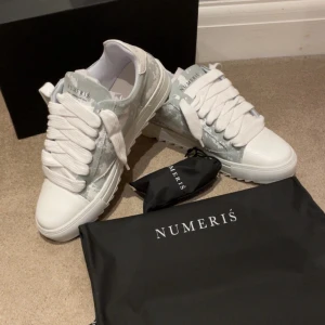 Numeris cloud - Snygga sneakers från Numeris med breda vita snören, rund tå och platt sula. Ovandelen är i ljusgrått och vitt med ett coolt camouflage-mönster och detaljer i skinn. Skorna går endast att få tag på i Storbritannien. Skorna är helt nya och aldrig använts. 