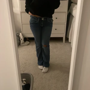 Blå bootcut jeans från Gina Tricot - Säljer ett par blå jeans från Gina Tricot i storlek 164. Modellen har bootcut-ben och låg midja, med klassiska fickor och egenklippt hål i knät💗