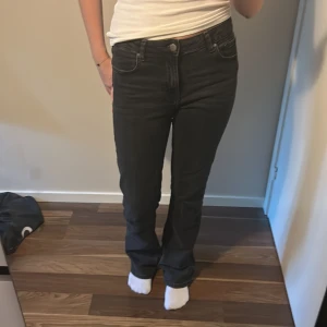 Svarta bootcut jeans - Snygga svarta jeans med klassisk femficksdesign och bootcut-ben. Jeansen har normal passform och midwaist, vilket ger en skön och stilren look. Materialet är jeans med lätt stretch för extra komfort. Perfekta till sneakers eller boots.