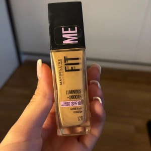 Maybelline Fit Me Foundation 120 - Maybelline Fit Me Luminous + Smooth foundation i nyansen 120. Kommer i en rektangulär glasflaska med svart pump och lock. Ger en naturligt fräsch finish och innehåller SPF 18 samt vitamin E. Passar normal till torr hud och har en ljus beige ton. Använt cirka 1/3