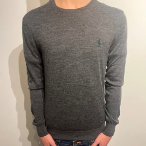 Grå 100% merinoulltröja Polo Ralph Lauren - Modell: 178 cm och väger 68 kg      Skick:7,9/10 på grund av flera igensyda hål vid kragen av tröjan syddes av en skräddare.  Vid frågor kontakta mig🙌