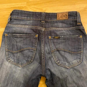 Mörkblå bootcut jeans från Lee W27 L31 - Snygga mörkblå jeans från Lee i modellen Desoto med klassisk bootcut passform. Jeansen har fem fickor, kontrastsömmar och Lee-logga på bakfickan. Tillverkade i slitstarkt denim med lätt tvättad look och låg midja.