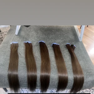 Slaviskt Tape extensions i 60 cm 200 gram - Säljer flera paket med brunt löshår i olika nyanser, alla med rak och silkeslen struktur. Håret är fäst med tape och passar perfekt för dig som vill ha längre och fylligare hår. Färgerna går från ljusbrun till mörkbrun och varje slinga är tjock och glansig.