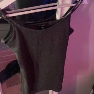 Mörkgrå linnetopp från Amisu - Snygg mörkgrå linnetopp från Amisu med smala axelband och enkel, rak passform. Toppen är ärmlös och gjord i mjuk bomull, perfekt för att styla med jeans eller kjol. Stilren och enkel design som funkar till många looks.