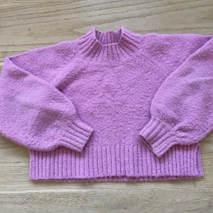 Rosa stickad tröja från Gina Tricot Young - Superfin rosa stickad tröja från Gina Tricot Young med bred ribbad mudd i nederkant och vid ärmslut. Tröjan har en högre ribbad hals och ballongärmar.