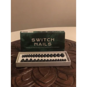 Switch Nails svarta glitter naglar - Säljer ett set med svarta lösnaglar från Switch Nails, täckta med holografiskt glitter som ger en riktigt cool effekt. Naglarna är i olika storlekar och har en snygg, spetsig form. Materialet är återvunnet plast och naglarna är återanvändbara. Perfekt för dig som vill ha statement-naglar.