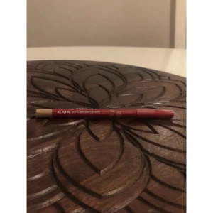 CAIA Eye Brightener penna - Säljer en CAIA Eye Brightener penna i nude/ljusbeige färg. Perfekt för att ljusa upp vattenlinjen och ge piggare blick. Pennan har en smal och lättanvänd form, med röd hylsa och beige spets. Enkel att applicera och passar till alla ögonmakeuper. 