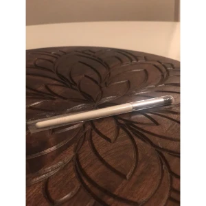 CAIA E20 ögonskuggsborste vit - Säljer en CAIA E30 ögonskuggsborste med vit skaft och silverfärgat fäste. Borsten har täta, mjuka syntetiska strån i svart och vitt, perfekt för att blenda och applicera ögonskugga med precision. Stilren design och lätt att använda för detaljerad ögonmakeup.