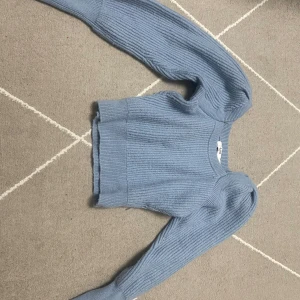 Ljusblå ribbstickad tröja från NA-KD - Superfin ljusblå ribbstickad tröja från NA-KD med croppad passform och långa ärmar. Tröjan har en rund halsringning och är gjord i ett mjukt stickat material som är perfekt för kyligare dagar.