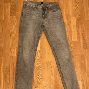 Grå slim fit jeans från BOSS - Snygga grå jeans från BOSS i modellen 020 Delaware. De har en slim fit-passform, klassisk femficksdesign och är tillverkade i stretchigt jeanstyg för extra komfort. Perfekta för dig som gillar en stilren och modern look.