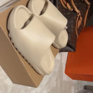 Adidas Yeezy Slide Bone strl 43 - Riktiga Adidas Yeezy Slide i färgen Bone, storlek 43. jätte snygga yeezy slides jag köpte i 2024 i USA, köpte för 300 $ = 3000 kr. Säljer pga: använder aldrig, är storlek 43 i M men passar även kvinnor 💗