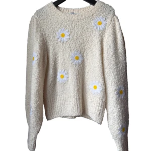 Beige stickad tröja med blommor & Other Stories - Supermysig beige stickad tröja från & Other Stories Paris Atelier, dekorerad med broderade vita och gula blommor över hela tröjan. Modellen har lång ärm och ribbad kant vid hals och nederdel. Perfekt för dig som gillar söta detaljer och vill ha en cozy vibe.