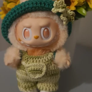 Grön virkad hatt med byxor. - Söt virkad hatt i mörkgrönt med ljusgrön blomdetalj och ljusgröna byxor. Perfekt för att ge en gullig touch till din Labubu 