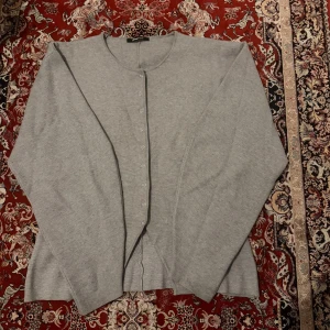 Ljusgrå kofta från Gina Tricot - En stilren ljusgrå kofta från Gina Tricot i storlek M. Koftan har rund halsringning, långa ärmar och knäppning framtill med små knappar. Tillverkad i mjukt stickat material som är perfekt för lager-på-lager. Enkel och clean look som funkar till allt. Den är en set, har kjolen till den också