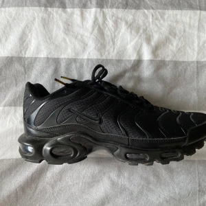 Svarta Nike sneakers storlek 46 - Säljer ett par helsvarta Nike sneakers med snygg vågig design på ovandelen och robust sula. Skorna har snörning och meshmaterial för bra andningsförmåga. Perfekta för dig som gillar sportig och clean stil. Nike-logga på sidan och plös.