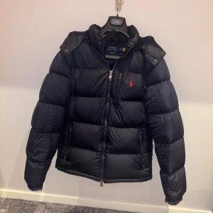 Mörkblå dunjacka från Polo Ralph Lauren - Säljer en mörkblå vinterjacka från Polo Ralph Lauren. Köpt på Ekbergs i Kristianstad förra vintern. Använd men med få tecken av användning, ända skadan på jackan är på ena fickan. Storlek L.