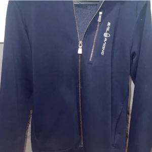 Marinblå jacka från Sail Racing - Säljer en mörkblå zip hoodie från Sail Racing pga att den blivit för liten för mig. Tröjan är i storlek 160 och har använts få tal gånger. Pris kan diskuteras