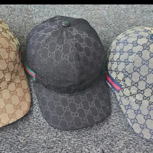 Gucci keps med GG-mönster - Säljer en klassisk Gucci keps med ikoniskt GG-mönster. Finns i svart, beige och beige med blått. Kepsen har böjd skärm, justerbar baksida och den typiska gröna/röda randen på sidan. Materialet är bomullscanvas och kepsen har en snygg streetstil.