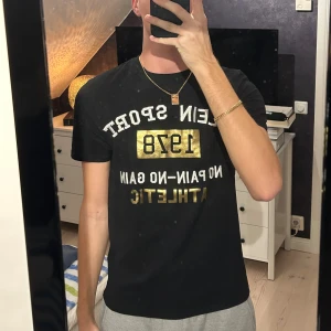 Svart Plein Sport t-shirt med guldtryck - Svart t-shirt från Plein Sport, tillverkad i mjuk bomull för skön passform.