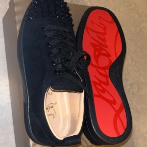 Christian Louboutin svarta sneakers med nitar - Säljer ett par Christian Louboutin sneakers i storlek 43. Skorna är helt nya och aldrig använda, levereras med originalkartong, dustbag och tillbehör. Färg: Svart med den klassiska röda sulan stilren och lyxig design som passar både till vardag och fest.  Äkta vara, köpta i butik. Perfekta för dig som vill ha ett par exklusiva sneakers i toppskick till ett bra pris!