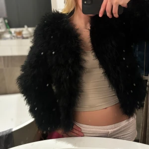 Svart fluffig pälsjacka - Säljer en svart fluffig pälsjacka med lång ärm och loose passform. Jackan har en cool och trendig look. Perfekt för dig som vill sticka ut och hålla dig varm under höst och vinter.