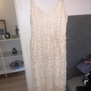 Champagnefärgad klänning med rosdetaljer - Superfin klänning från Vero Moda i champagnefärgad ton med 3D-blommor över hela tyget. Klänningen är oanvänd och har prislappen kvar, nypris är 699kr
